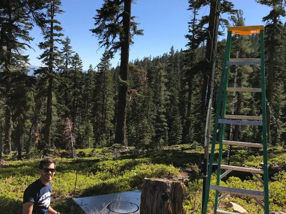 Josh Sturtevant in a mountain forest setting up research equipment.