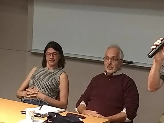 Gregg Garfin holding a microphone and talking to other researchers in a conference room.