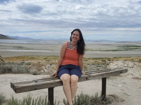 Nicole on a bench in front of sand and a body of water