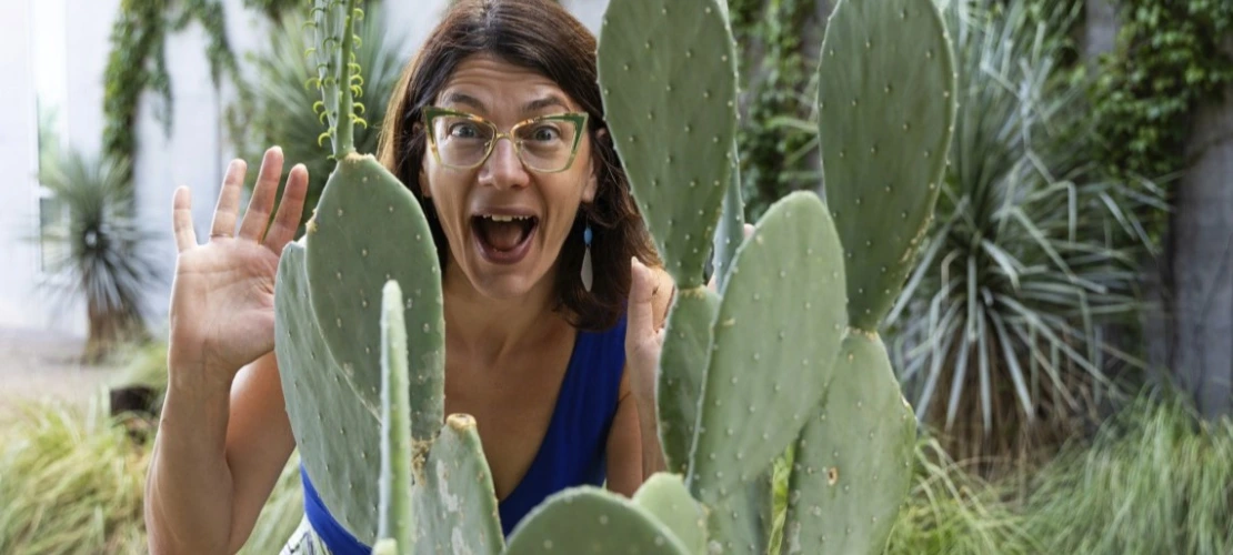 A photo of Elise Gornish just behind a short green cactus