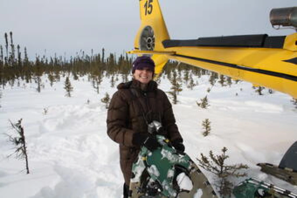 Laura Thompson standing next to a helicopter in the snow