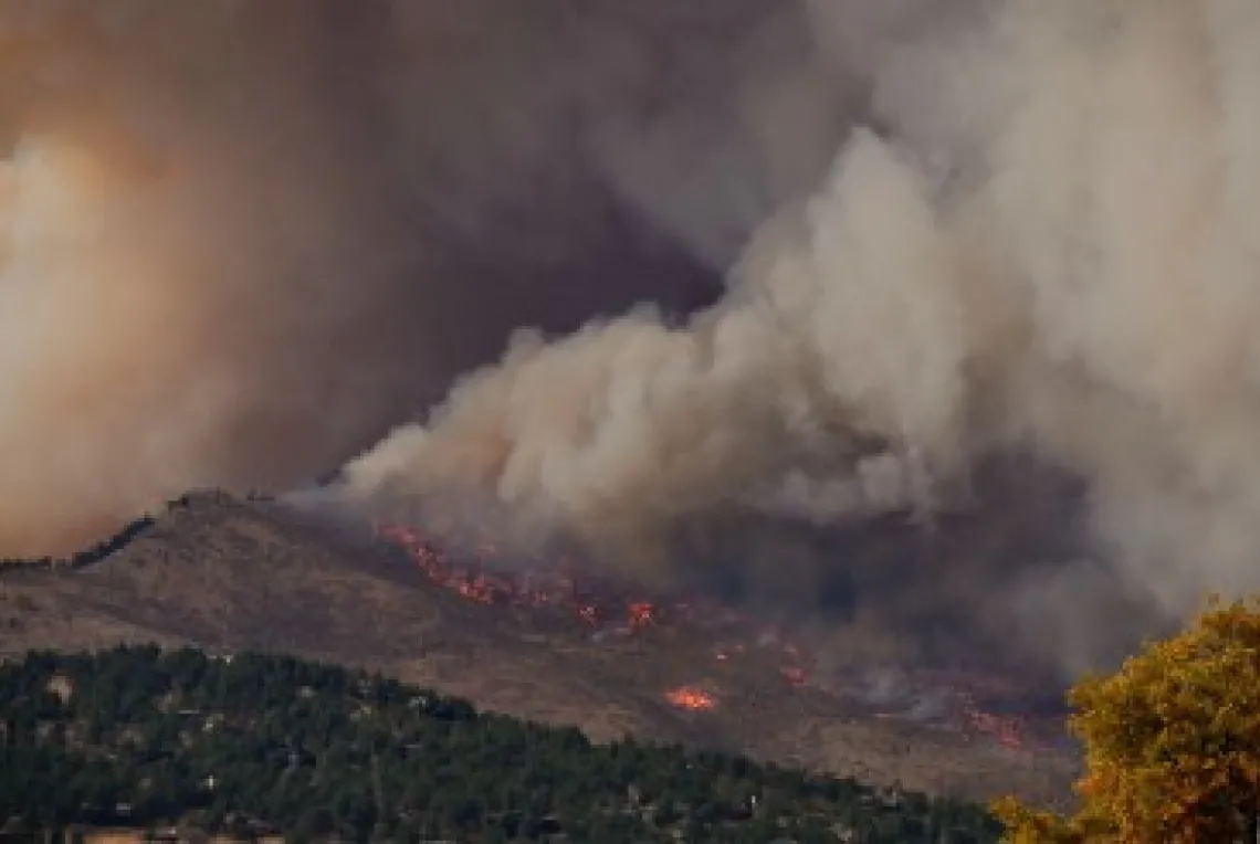 A large amount of smoke coming from a fire on a mountain range.