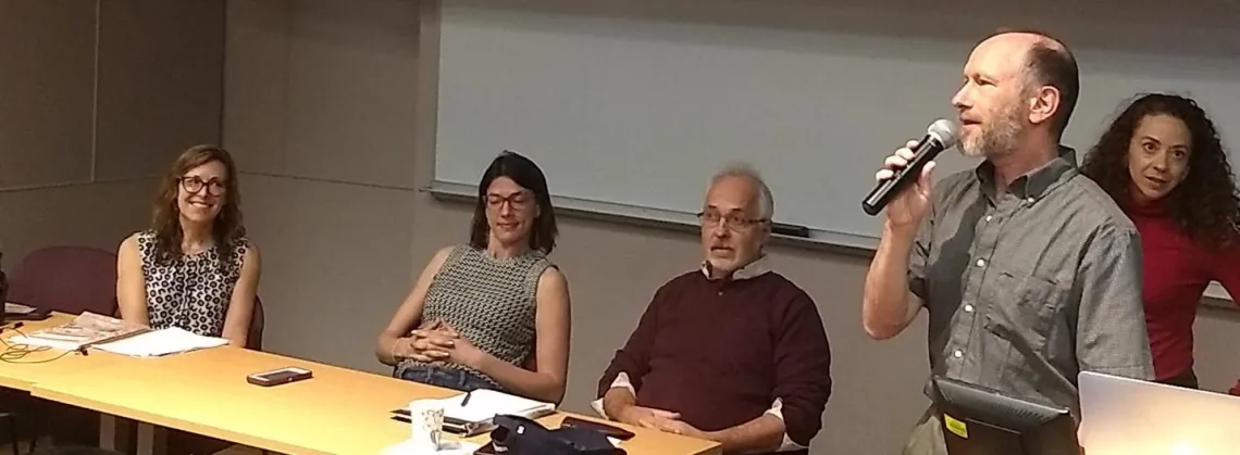 Gregg Garfin holding a microphone and talking to other researchers in a conference room.