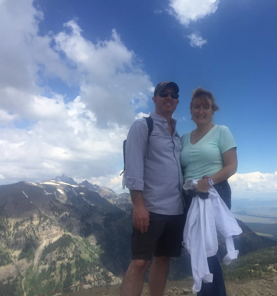 Corrina and one other person standing on a hill in front of a blue sky