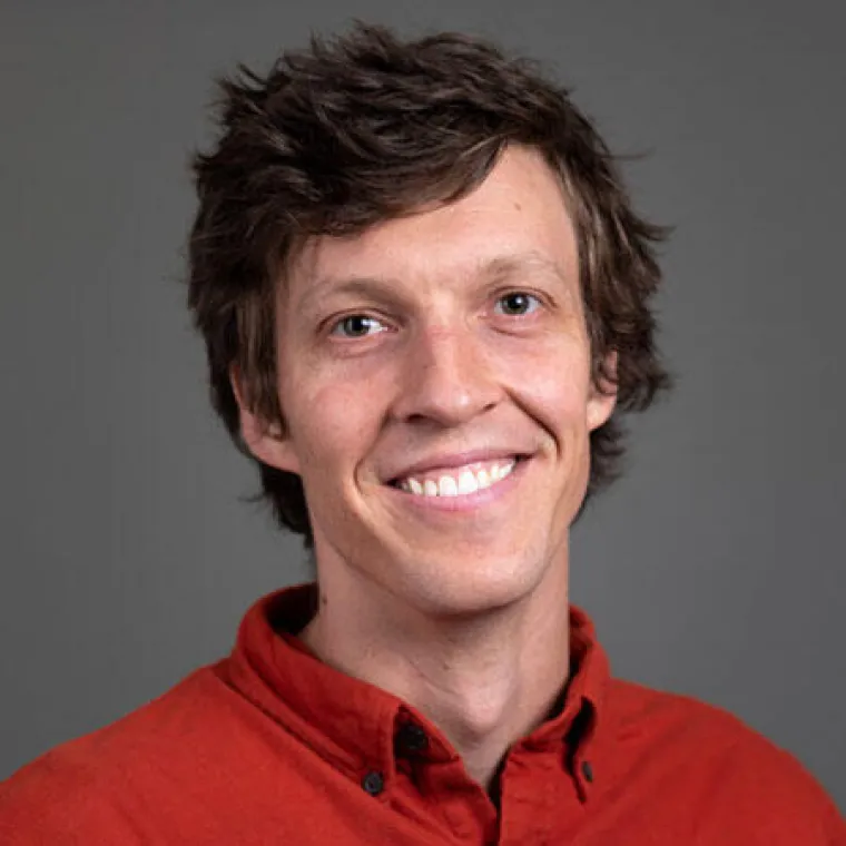 Man wearing red shirt in front of grey bacjground