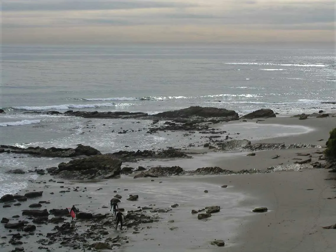 A beach in the early morning being soaked by small waves.